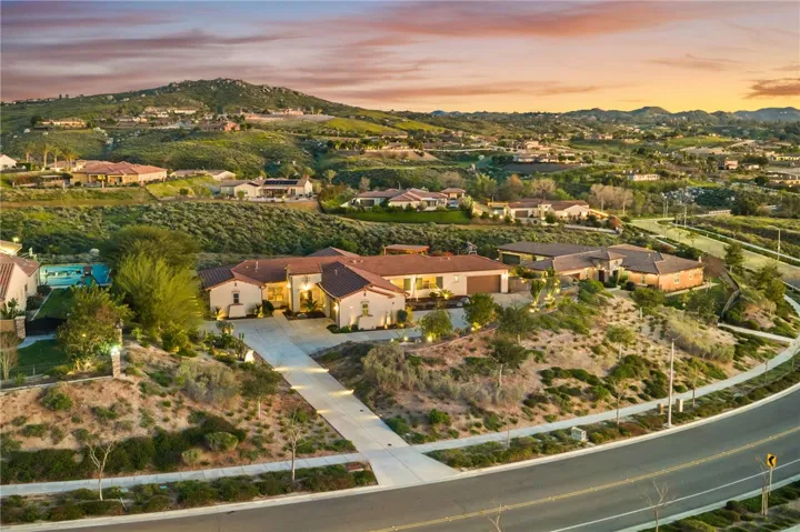 Broad aerial view emphasizes the home’s corner-like positioning, generous lot presence, and elevated neighborhood setting.