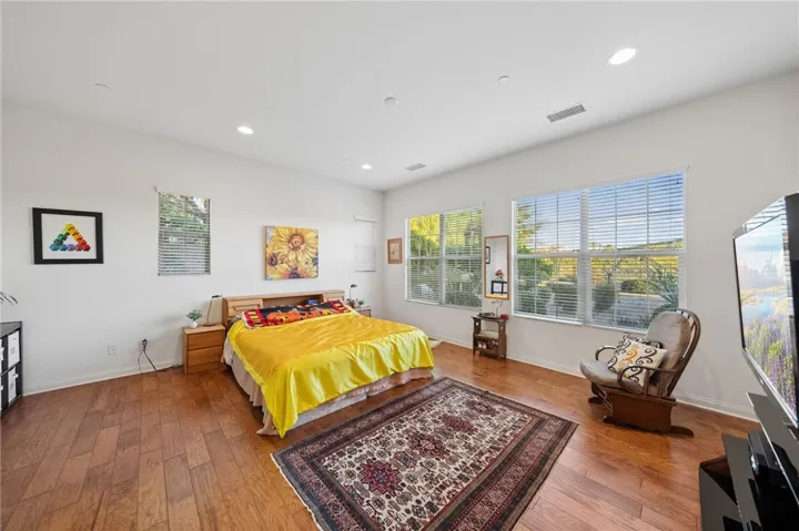 Spacious primary bedroom features warm wood flooring, abundant natural light, and plenty of room for a sitting area.
