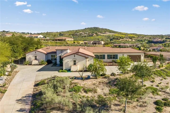 Single-story residence with a long driveway, desert landscaping, and an elevated homesite that showcases the surrounding hillside setting.