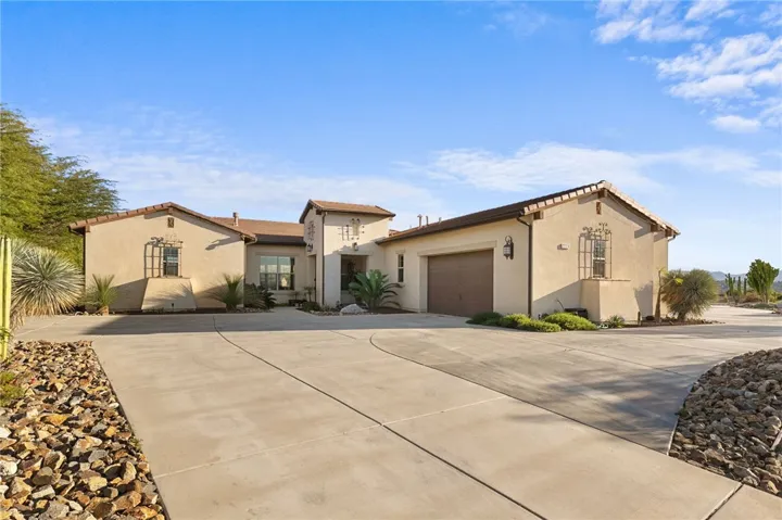 Single-story exterior features a covered entry, arched architectural details, and well-maintained drought-conscious landscaping.