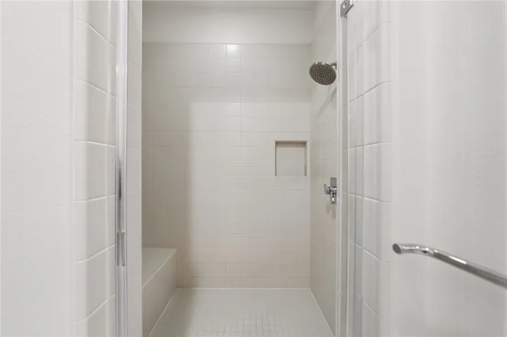 Roomy walk-in shower offers a simple, clean design with built-in niche and bench seating.