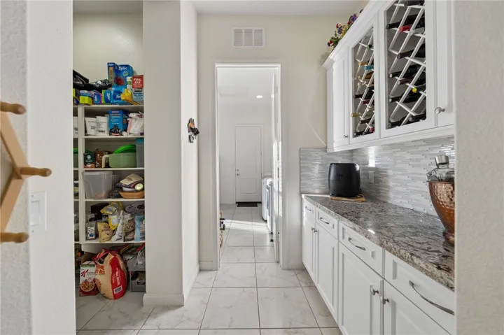 Additional prep and storage space includes built-in cabinetry, countertop workspace, wine storage, and a large walk-in pantry.