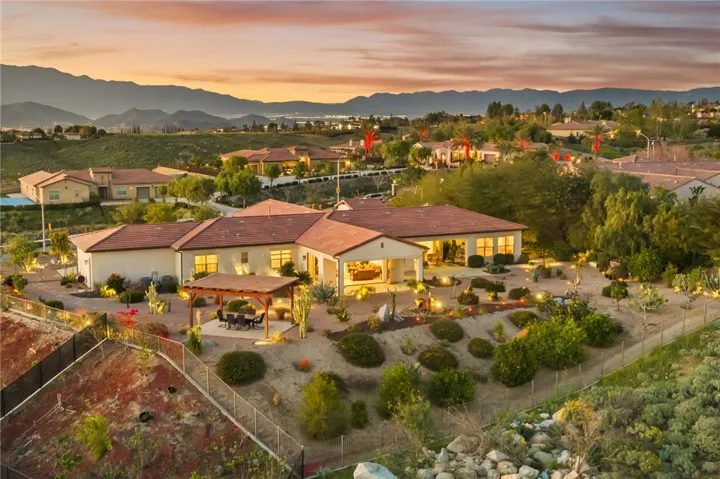 Twilight aerial highlights the home’s expansive backyard design, pergola entertaining area, and beautifully illuminated outdoor setting.