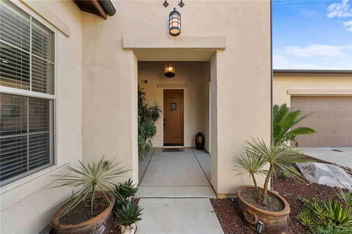 Inviting front porch entry offers a sheltered arrival with warm architectural character and attractive potted accents.