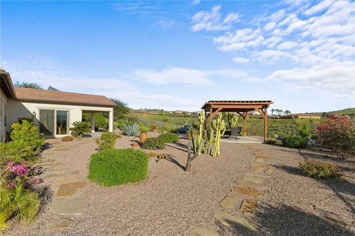 Low-maintenance backyard combines gravel pathways, sculpted desert plantings, and multiple outdoor gathering areas.