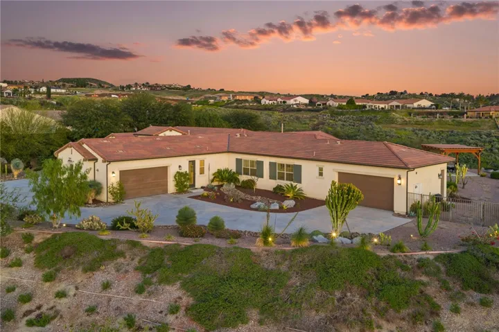 Elevated twilight view captures the home’s prominent homesite, expansive frontage, and surrounding hillside backdrop.