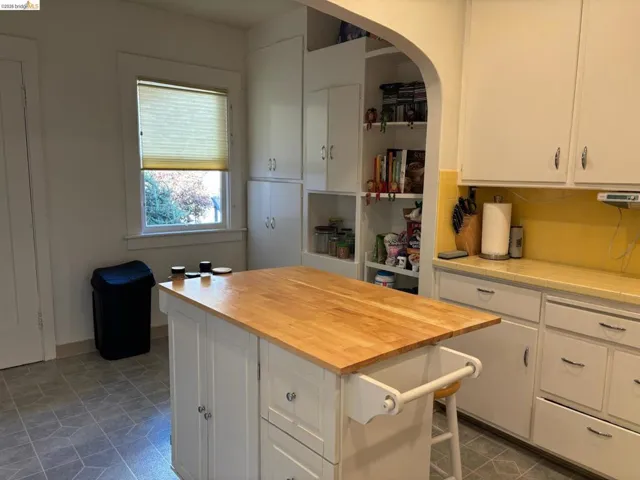 Kitchen featuring white cabinetry, a kitchen island, butcher block countertops, arched walkways, and tasteful backsplash