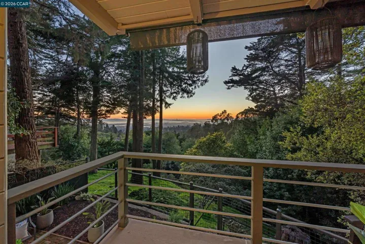 A covered deck overlooks serene treetops with sweeping views toward the Bay and distant skyline, offering a peaceful setting for morning coffee or sunset gatherings.