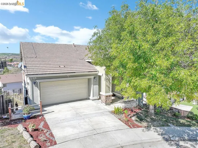 View of front of property with a tiled roof, concrete driveway, stucco siding, an attached garage, and stone siding