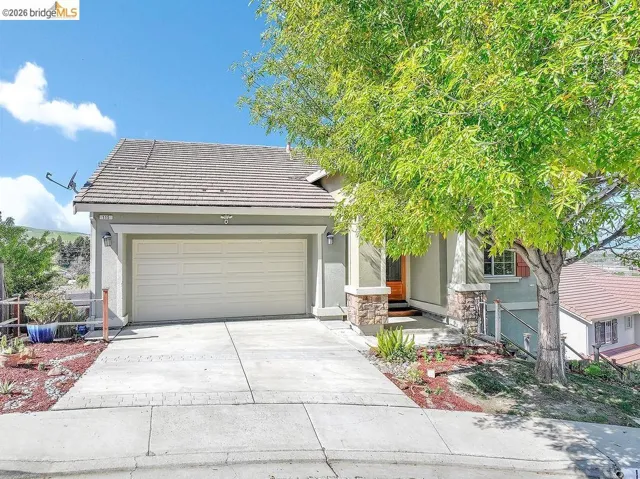 Obstructed view of property featuring stucco siding, a tile roof, driveway, a garage, and stone siding