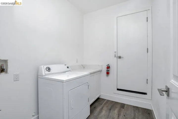 Laundry room with washer / dryer, dark wood-style floors, and cabinet space