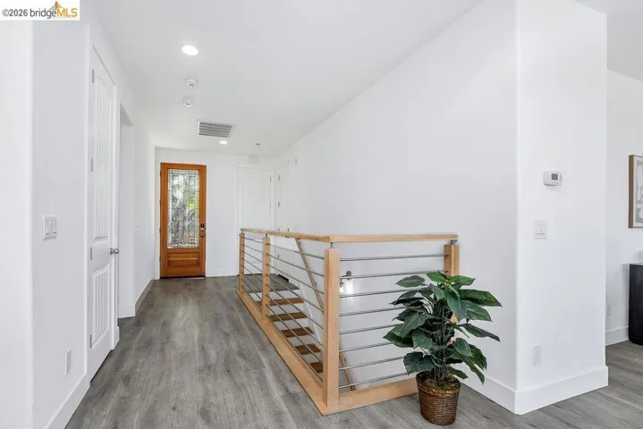 Hall with an upstairs landing, light wood-style flooring, and recessed lighting