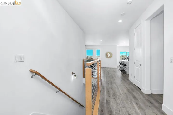 Hallway with an upstairs landing, light wood finished floors, and recessed lighting