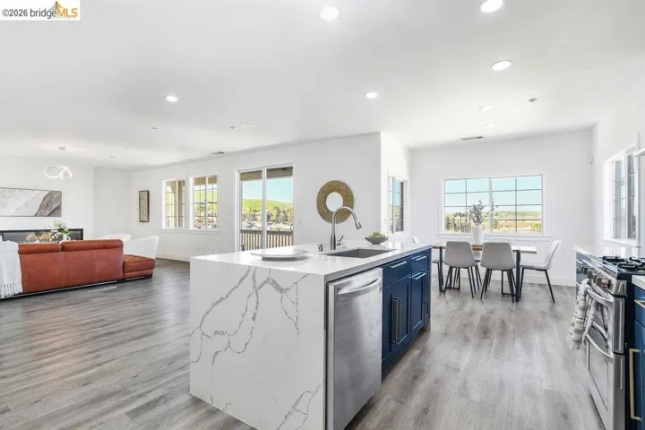 Kitchen with open floor plan, light stone counters, an island with sink, stainless steel appliances, and recessed lighting