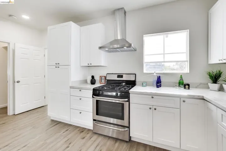 Kitchen featuring stainless steel gas stove, white cabinetry, and light wood-style flooring