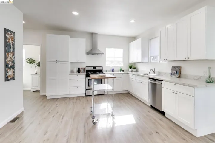 Kitchen featuring white cabinets, stainless steel appliances, light countertops, light wood-type flooring, and recessed lighting