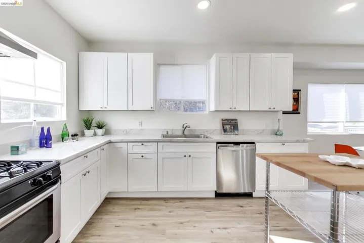 Kitchen featuring white cabinets, stainless steel appliances, light wood finished floors, recessed lighting, and range hood