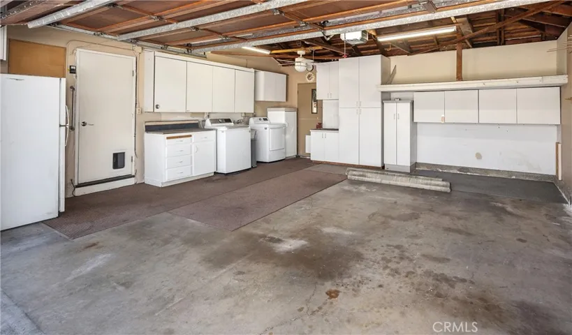 Garage interior with washer, dryer, utility sink, storage and refrigerator.