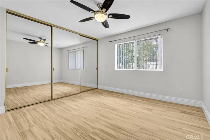 Primary bedroom #2 with mirrored doors with organizers and views to the enclosed backyard, trees and flowers