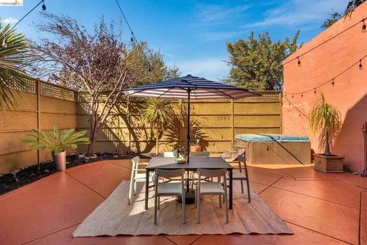 Fenced backyard featuring a patio area, outdoor dining area, and a hot tub