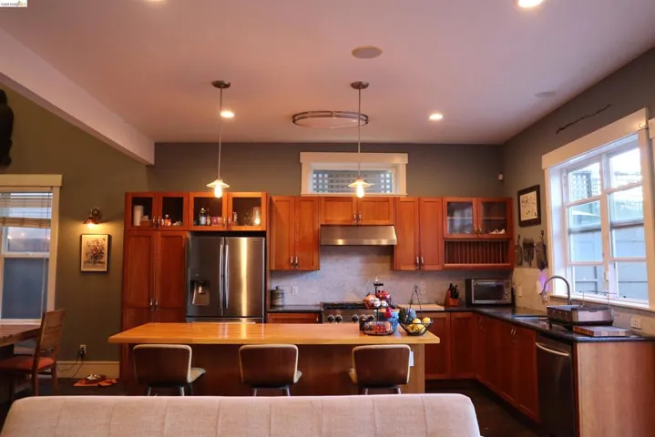 Kitchen with glass fronted cabinets, stainless steel appliances, wood finish cabinetry, a kitchen island, and wood counters