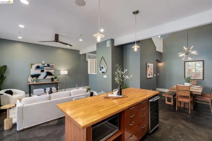 Kitchen with wooden counters, stainless steel microwave, open floor plan, wine cooler, and finished concrete floors