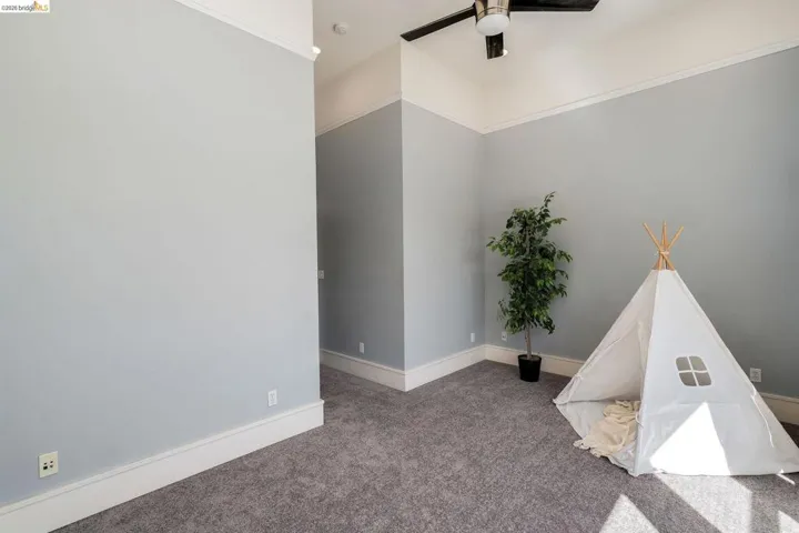 Carpeted spare room with ceiling fan and baseboards