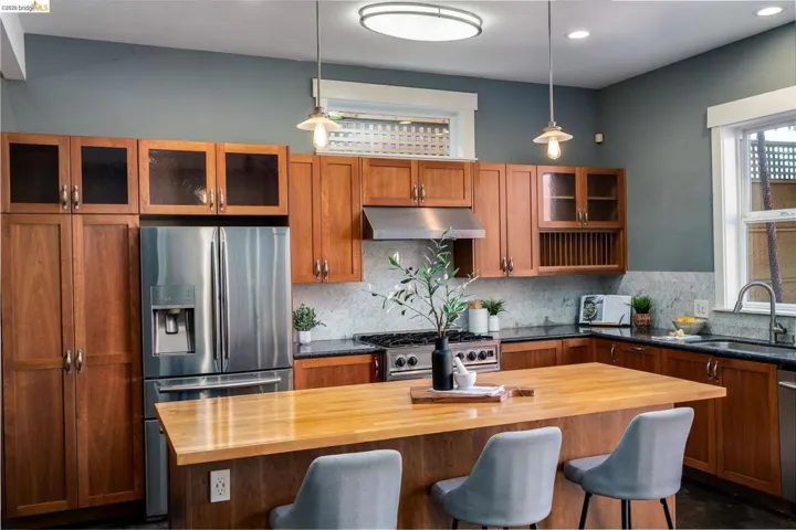 Kitchen with glass fronted cabinets, wood finish cabinetry, stainless steel appliances, and wood counters