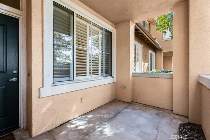 Front Patio – Private covered patio offers a sheltered outdoor sitting area just off the front entry, framed by large windows and stucco columns.