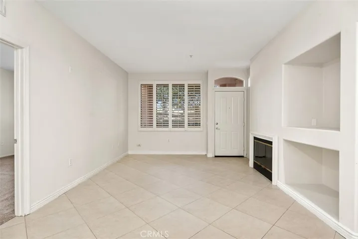 Living Room – Spacious living area showcases plantation shutters, built-in niches, and a fireplace that adds warmth and character to the room.