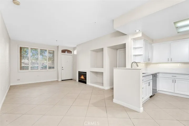 Kitchen and Living Area – Open-concept layout blends the kitchen and living room, creating a bright, functional space for daily living and entertaining. Fire shown in fireplace is digitally enhanced.