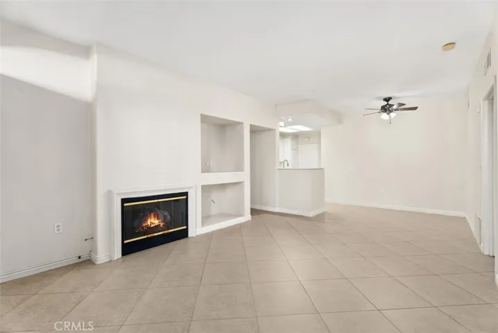 Living Room – Open-concept living space with tile flooring, ceiling fan, and a functional layout ideal for everyday living and entertaining. Fire shown in fireplace is digitally enhanced.
