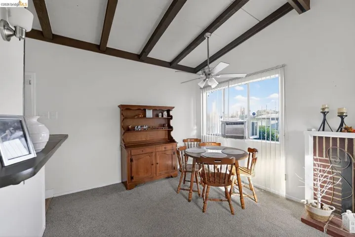 dining space with a ceiling fan, light carpet, vaulted ceiling, and cooling unit