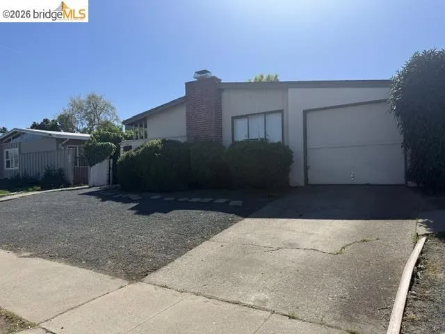 view of front facade featuring an attached garage, concrete driveway, and a chimney