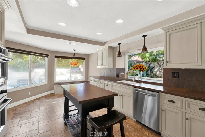 North view of remodeled kitchen looking towards backyard of kitchen with extended dining or eating area. Upgraded stainless appliances including dishwasher. Vaulted ceiling with recessed lights. Cabinets have under cabinet lighting. Milgard Windows. Travertine Flooring.