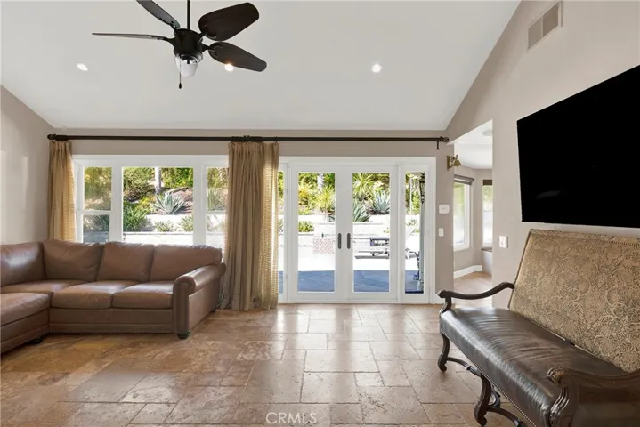 Family Room open to the living & Dining Room and the kitchen. Custom double pane doors have been removed but are saved in the garage. Newly installed vinyl slider to exterior. Vaulted ceiling, ceiling fan, recessed lights, travertine flooring.