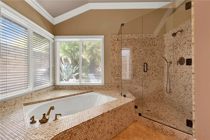 Primary Suite Custom Remodeled Walk -in Soaking Tub and Separate Walk In Enlarged Shower with Custom Frameless Glass Doors and Hardware. Crown Molding, Custom Wood Shutters over Milgard Windows.
