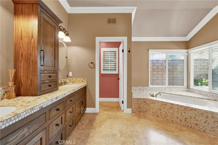 Upgraded Primary Suite Vanities and Center Counter Storage, Crown Molding, Custom Panel Doors and Hardware, Separate Walk-in Soaking Tub, Custom Wood Shutters over Milgard Windows.