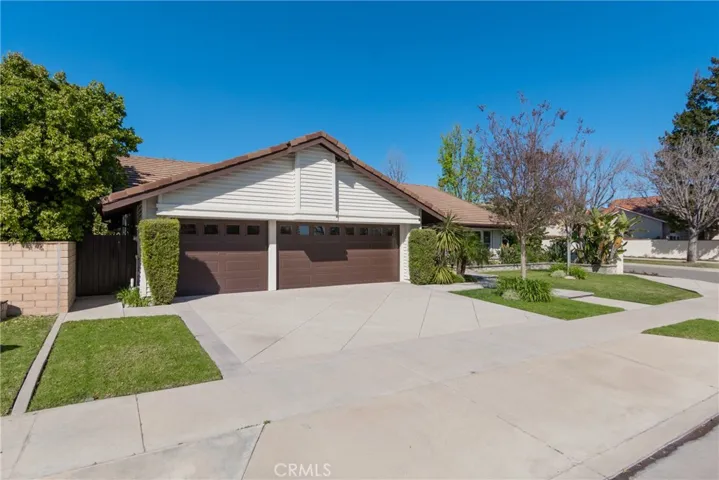 Three car garage with garage door opener and loads of parking area in front of garage on cement driveway.