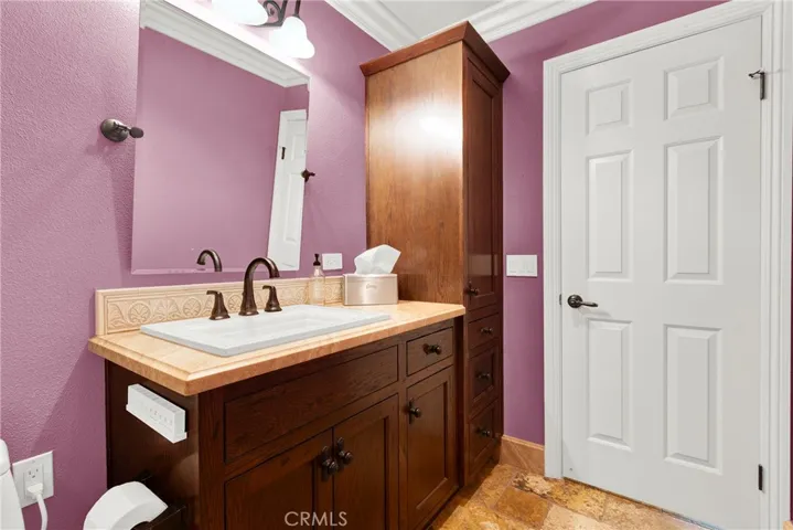 Guest Bathroom upgraded Vanity, Storage Closet, Mirror and Crown Molding. Custom Panel Door and Hardware and Travertine Flooring.