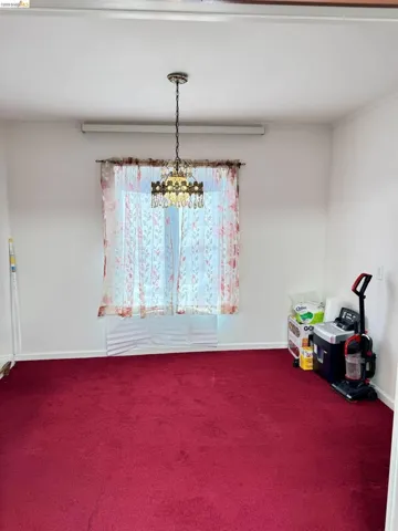 Unfurnished dining area with dark colored carpet and baseboards