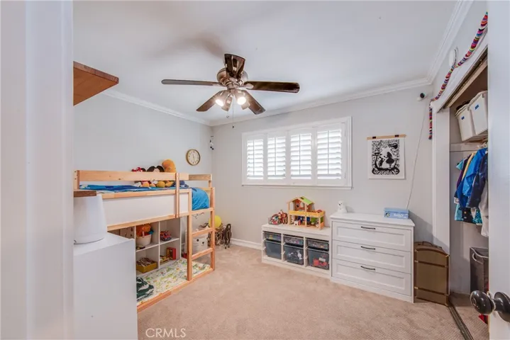 Bedroom 3 has a ceiling fan and large window with plantation shutters and overlooks the backyard.