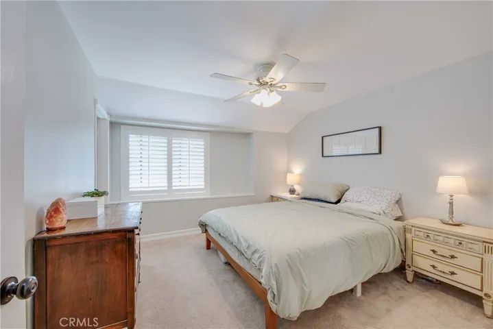 The primary bedroom is in the front of the home and features a ceiling fan and a large window with plantation shutters.