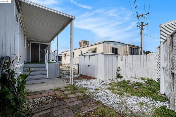 Fenced backyard featuring a storage shed, a gate, and a patio area