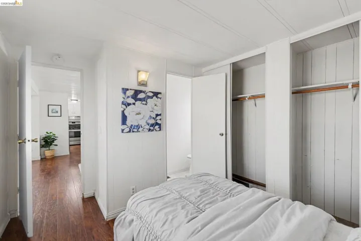 Bedroom with dark wood-type flooring and multiple closets