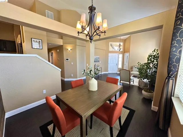 Dining space with dark wood-style floors, a chandelier, and a high ceiling
