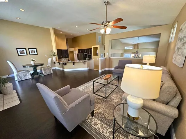 Living area featuring wood finished floors, a ceiling fan, hanging lights, and lofted ceiling