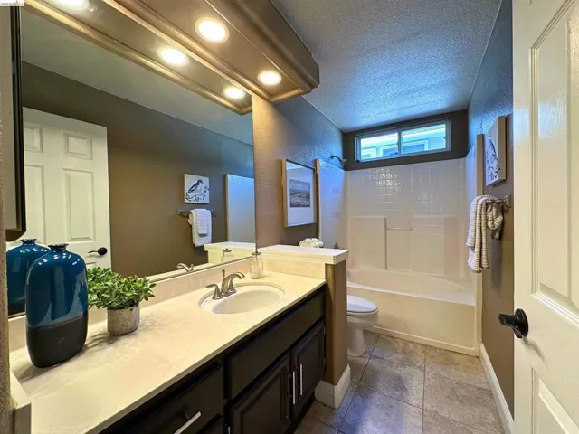 Full bathroom with vanity, a textured ceiling, shower / bathtub combination, and a textured wall