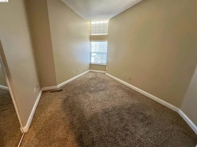 Spare room featuring dark carpet and baseboards