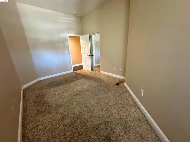 Unfurnished room with dark colored carpet and baseboards